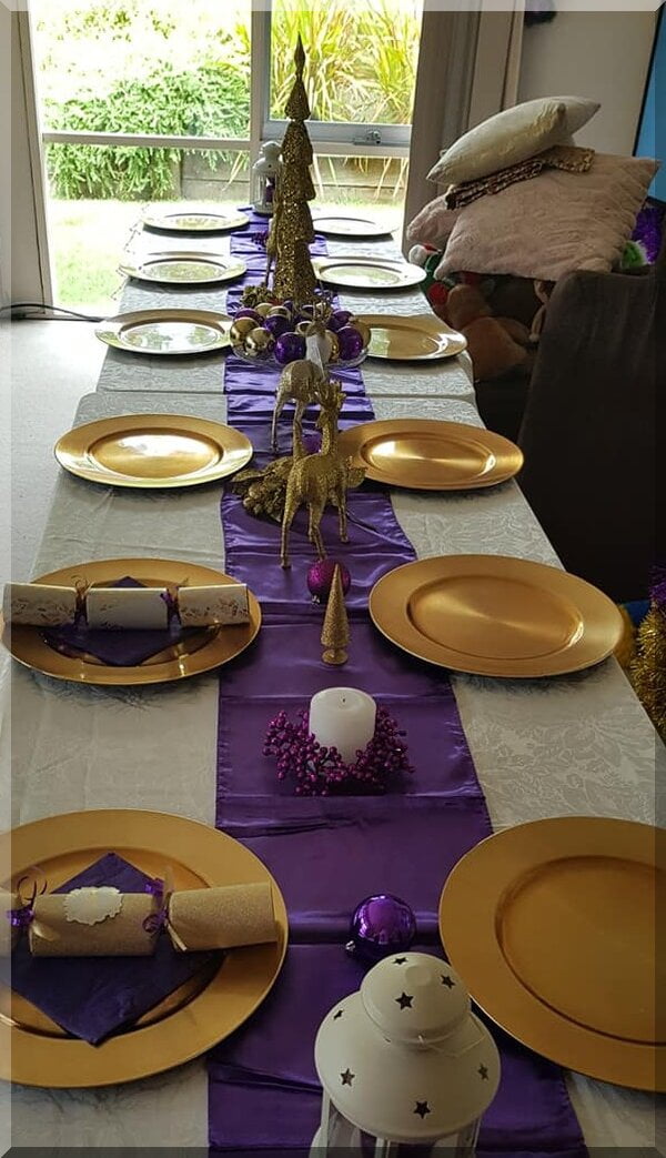 Purple and gold themed table setting with reindeer centrepieces
