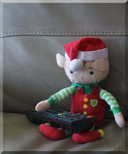 Christmas elf relaxing on couch with a remote control