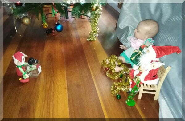Christmas elf taking a Santa photo with a baby elf and a large doll
