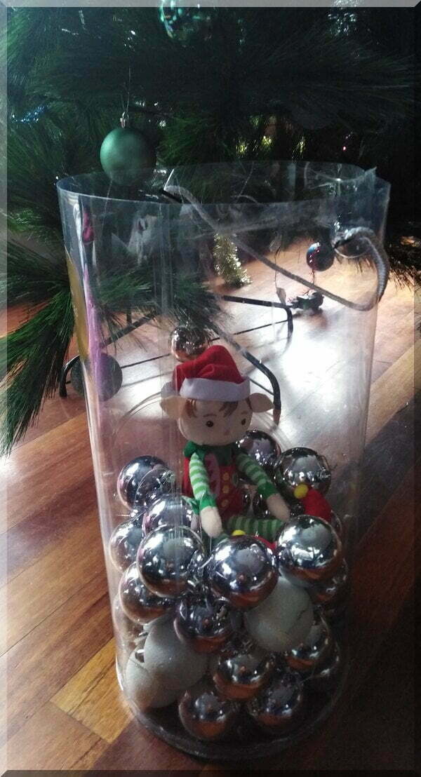 Christmas elf sitting in a bauble container