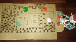 Christmas Elves sitting at a pacman board made of cardboard and malteasers